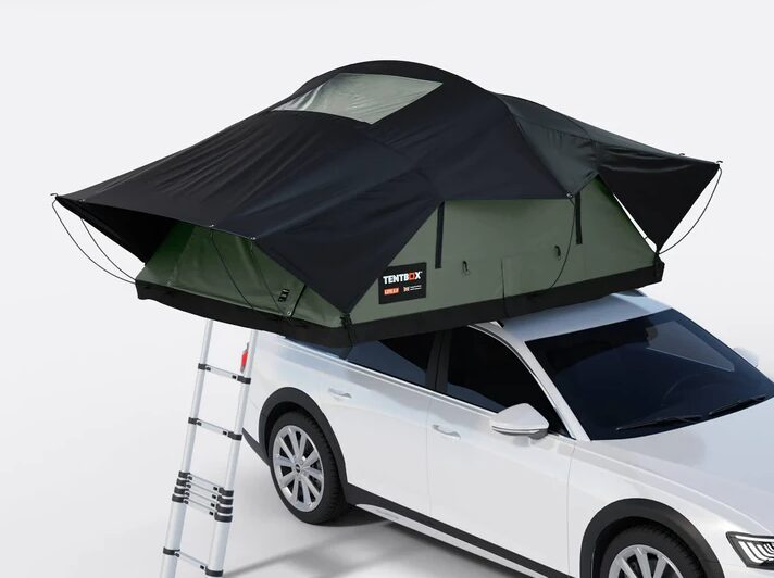 A TentBox rooftop tent set up beside a lake with two campers and a French Bulldog enjoying the sunset, representing TentBox camping adventures in the UK.